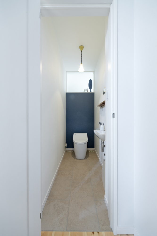 ホワイトカラーで統一されたトイレ、奥の壁のブルーがアクセントに。
